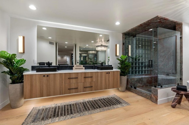 full bath featuring double vanity, recessed lighting, a stall shower, a sink, and wood finished floors