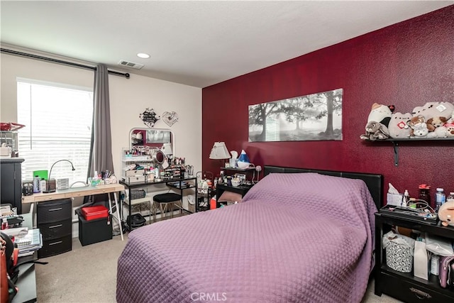 bedroom with visible vents, carpet flooring, and a textured wall