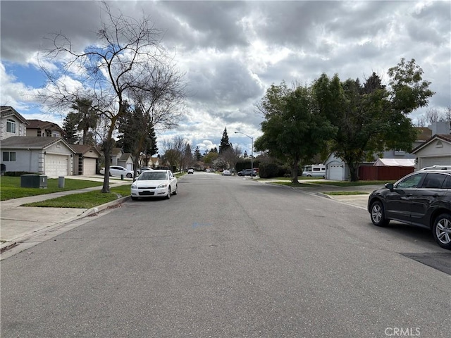 view of street with sidewalks, a residential view, street lights, and curbs