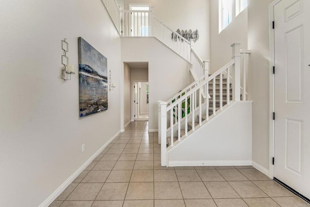 foyer with a high ceiling, plenty of natural light, and tile patterned flooring