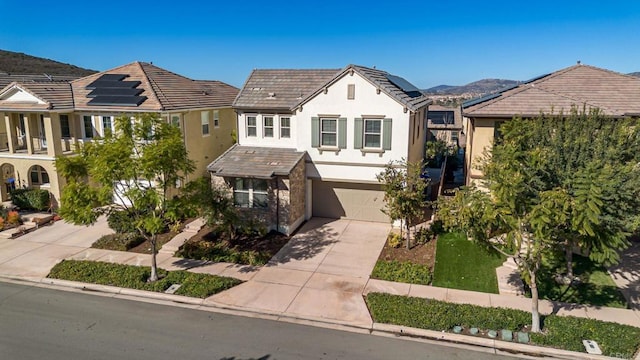 view of front of property featuring an attached garage, concrete driveway, solar panels, and stucco siding