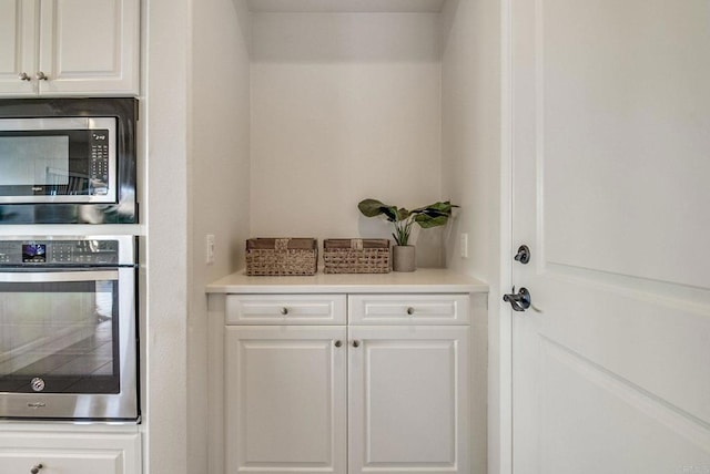 interior space with appliances with stainless steel finishes, light countertops, and white cabinets