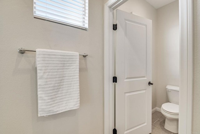 bathroom with tile patterned flooring, baseboards, and toilet