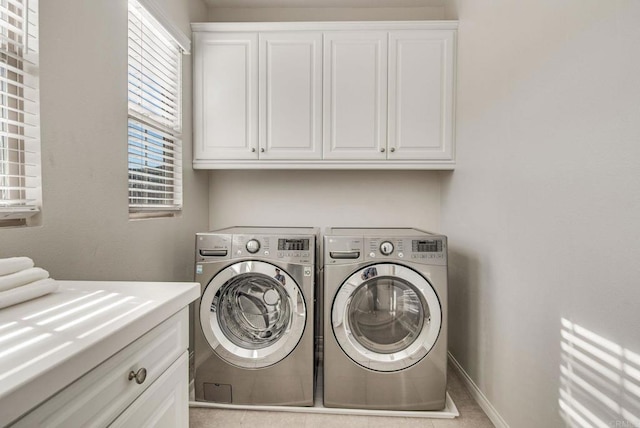 laundry area with washing machine and clothes dryer, cabinet space, and baseboards