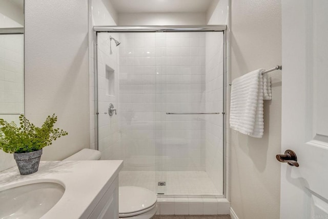 bathroom with toilet, a stall shower, and vanity