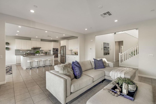 living area featuring stairway, light tile patterned flooring, visible vents, and recessed lighting