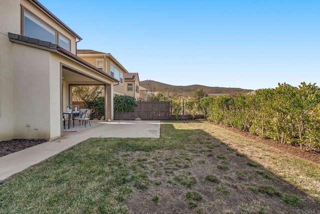 view of yard featuring a mountain view, fence, and a patio