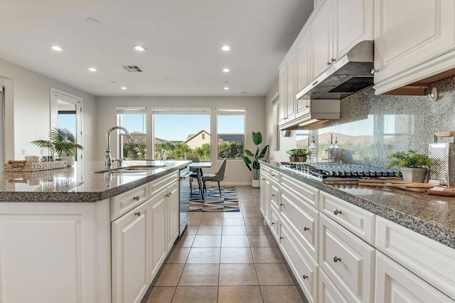 kitchen with light tile patterned floors, stainless steel appliances, decorative backsplash, a sink, and under cabinet range hood