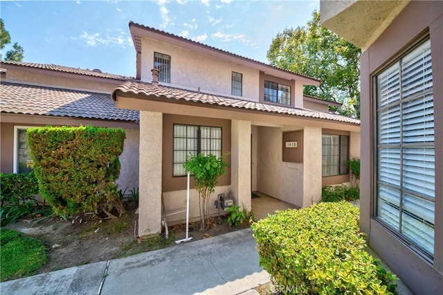 exterior space with stucco siding and a tile roof