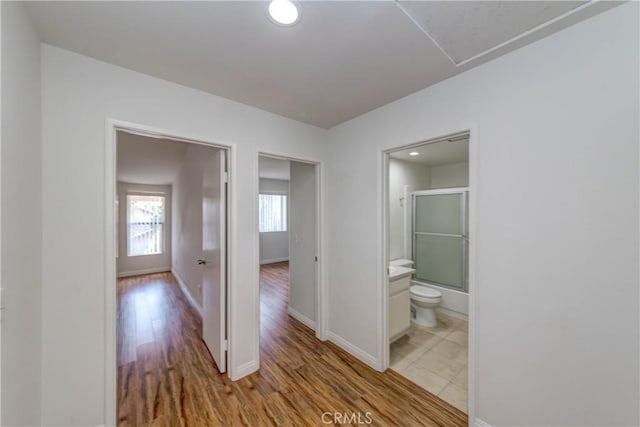 corridor featuring baseboards and light wood finished floors