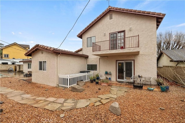 back of property featuring a balcony, fence, a patio, and stucco siding