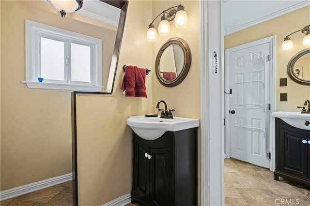 bathroom with a sink, two vanities, baseboards, stone finish floor, and crown molding