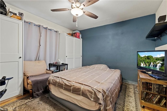 bedroom featuring ceiling fan, baseboards, and wood finished floors