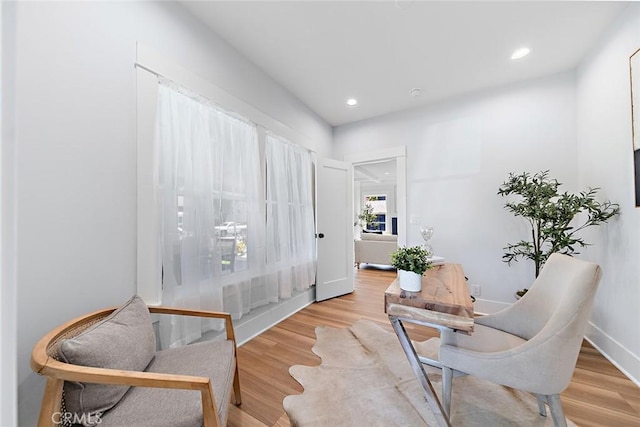 living area featuring baseboards, light wood-style flooring, and recessed lighting