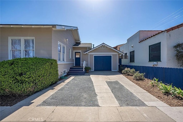 view of front of property featuring driveway, an attached garage, and fence