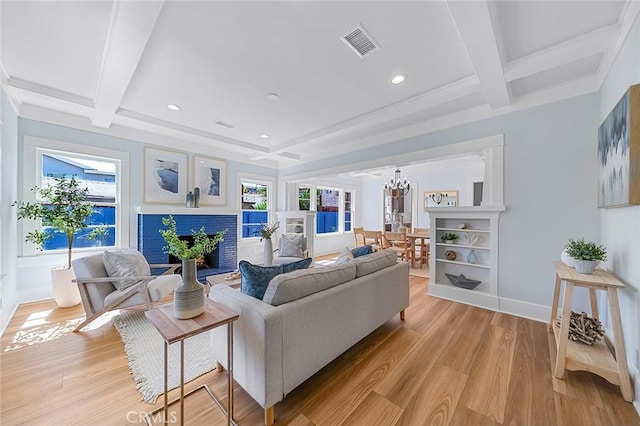 living room with a warm lit fireplace, beam ceiling, light wood-type flooring, and visible vents