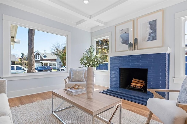 sitting room featuring a fireplace with raised hearth, coffered ceiling, wood finished floors, baseboards, and beam ceiling