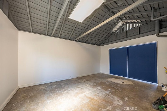 interior space featuring lofted ceiling with beams, concrete floors, and baseboards