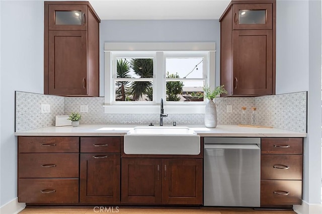 kitchen featuring tasteful backsplash, glass insert cabinets, a sink, and stainless steel dishwasher