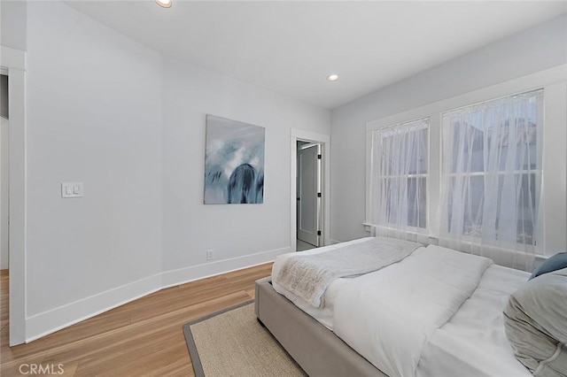 bedroom with baseboards, wood finished floors, and recessed lighting