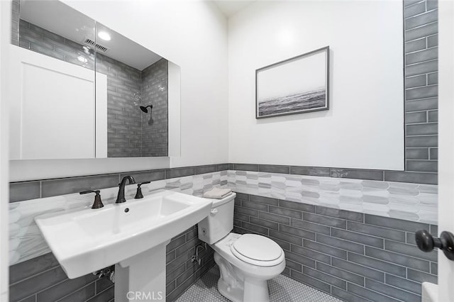 full bath with tile patterned flooring, toilet, visible vents, tile walls, and tiled shower