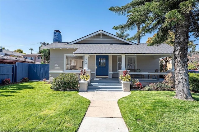 bungalow-style house featuring a porch, a chimney, a front yard, and fence