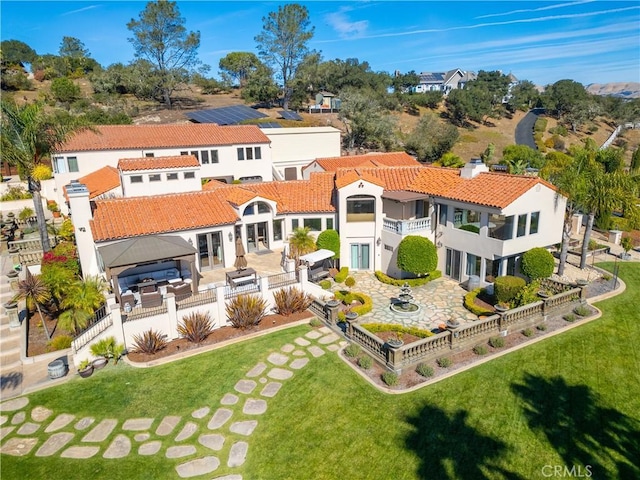 rear view of house featuring a gazebo, a fenced backyard, a patio area, a balcony, and a lawn