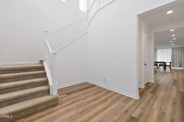 staircase featuring recessed lighting, wood-type flooring, and baseboards