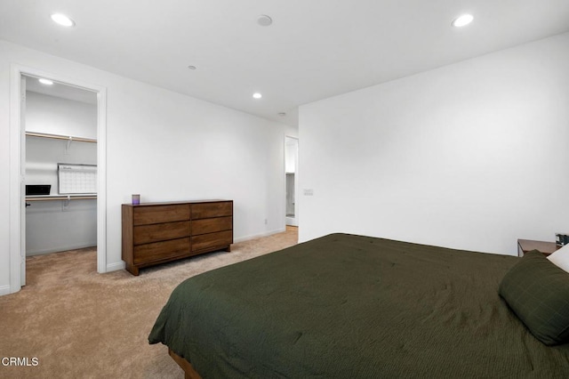 bedroom with light carpet, baseboards, a walk in closet, a closet, and recessed lighting