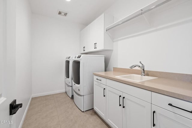 laundry area featuring light tile patterned floors, a sink, baseboards, washer and dryer, and cabinet space