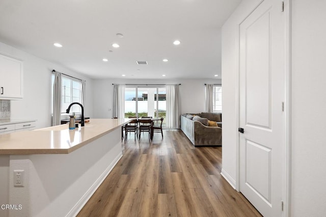 kitchen featuring light wood-style flooring, a sink, white cabinets, light countertops, and plenty of natural light