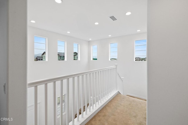 hall featuring carpet floors, recessed lighting, visible vents, and an upstairs landing