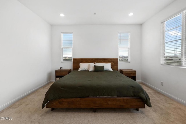 bedroom with light carpet, baseboards, and multiple windows