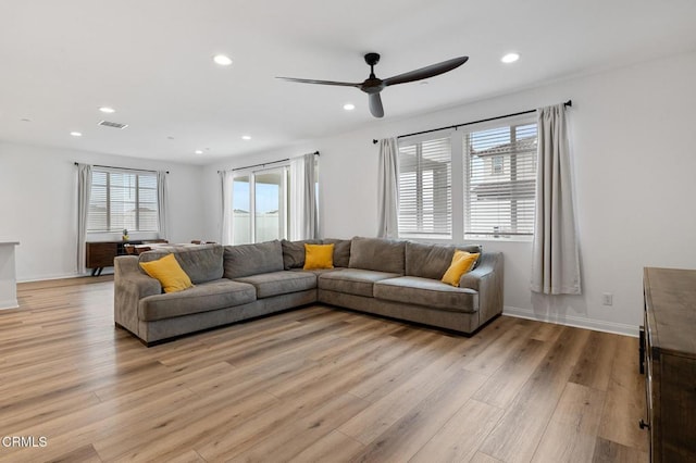 living room featuring light wood-type flooring, visible vents, baseboards, and recessed lighting