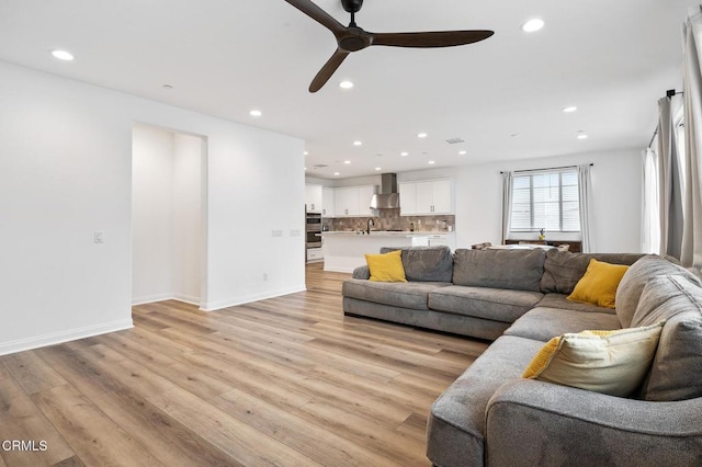 living room with baseboards, light wood finished floors, and recessed lighting