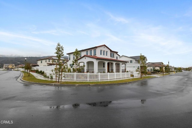 view of front of house featuring a tiled roof, a fenced front yard, and a residential view