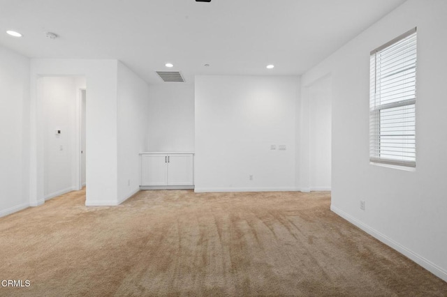 empty room featuring light colored carpet, recessed lighting, visible vents, and baseboards