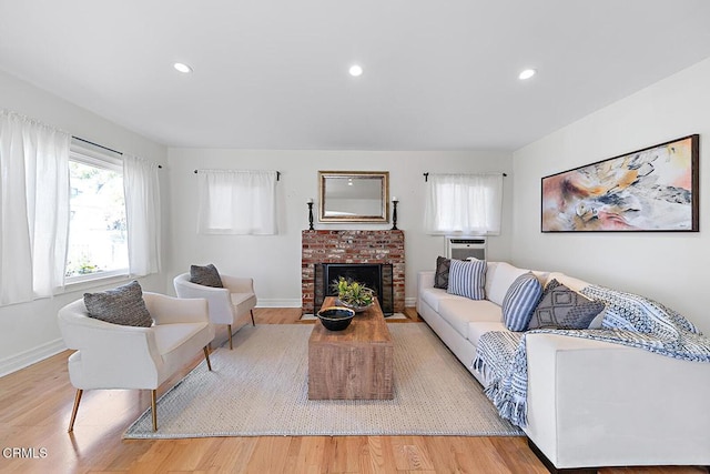 living area with light wood-style flooring, a fireplace, baseboards, and recessed lighting