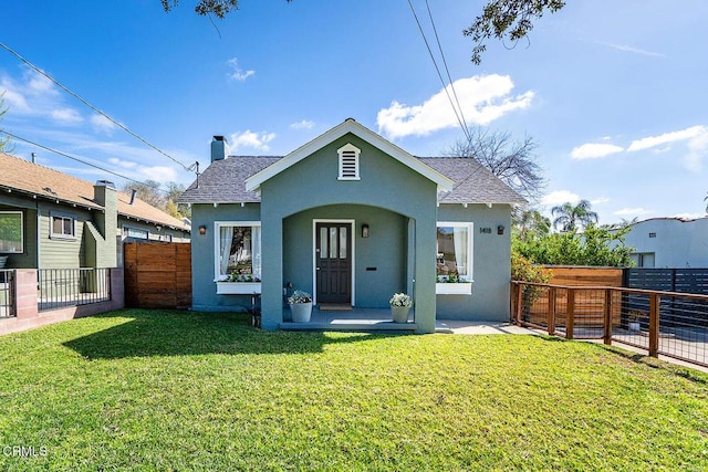 back of property with roof with shingles, a yard, fence, and stucco siding