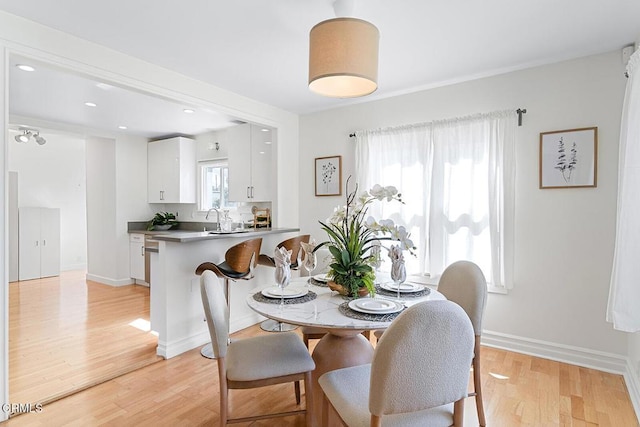 dining space featuring light wood-style flooring and baseboards