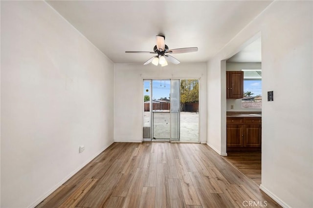 unfurnished room with a ceiling fan, baseboards, and light wood finished floors