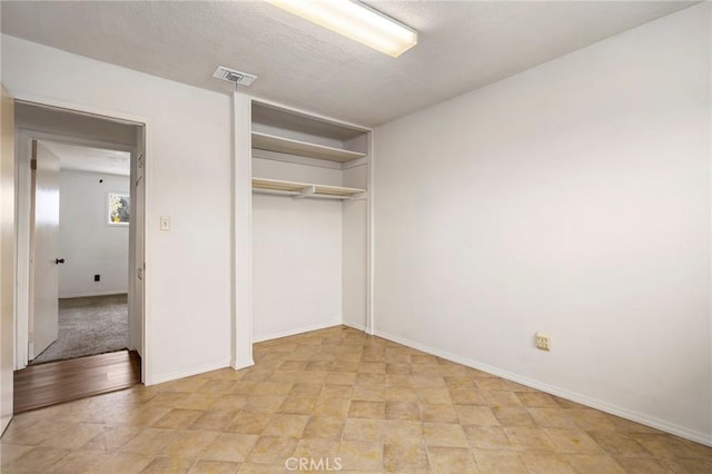 unfurnished bedroom featuring baseboards, a textured ceiling, visible vents, and a closet