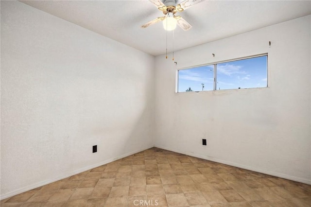 spare room featuring a ceiling fan and baseboards