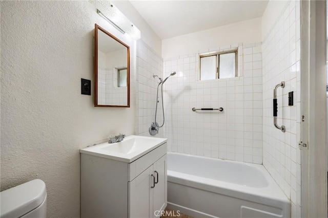 full bath featuring a textured wall, tub / shower combination, vanity, and toilet