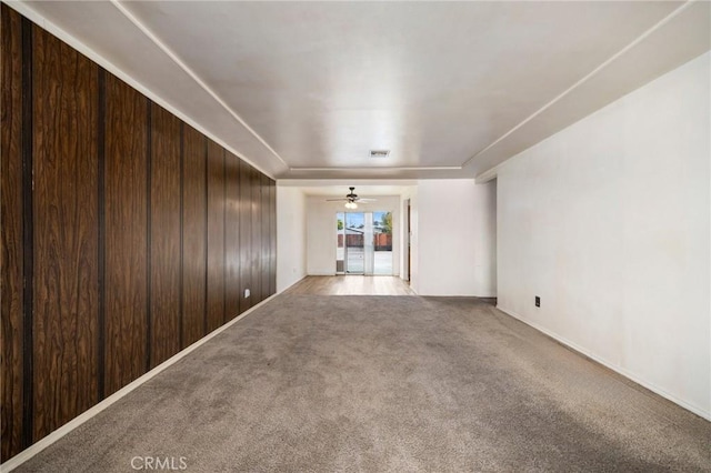 spare room with wood walls, ceiling fan, visible vents, and carpet flooring