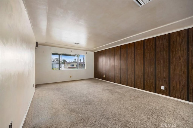 empty room featuring wood walls, carpet, and visible vents