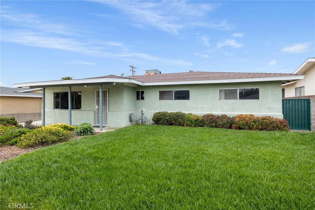 back of property with a lawn and stucco siding