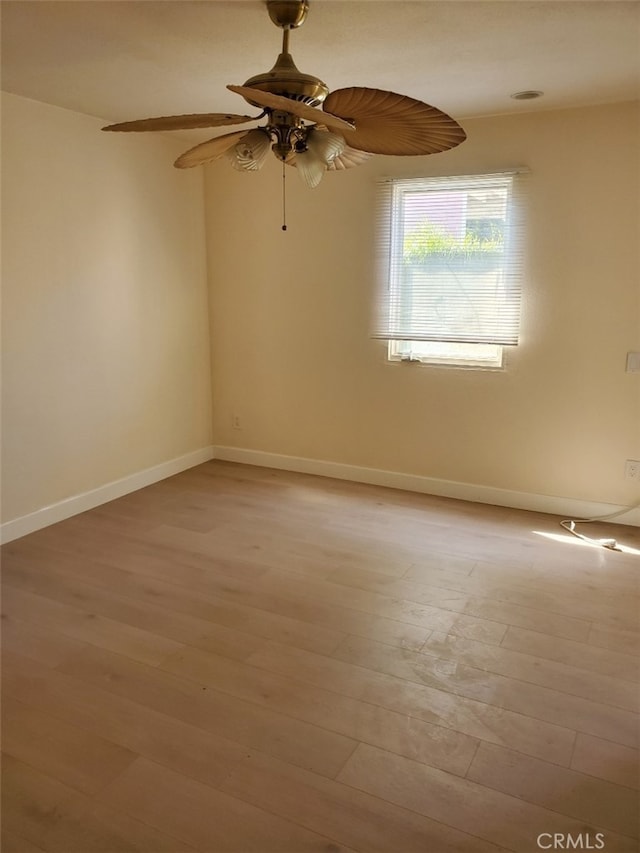 spare room with light wood finished floors, a ceiling fan, and baseboards