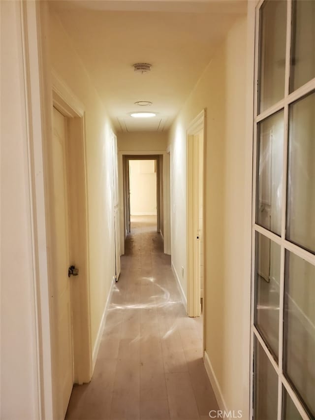 hallway featuring wood finished floors and baseboards