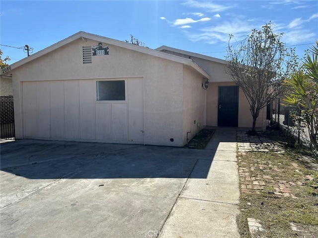 view of front of house featuring driveway, fence, and stucco siding